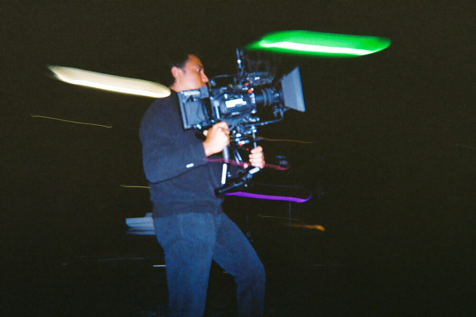Camera operator in motion, smeared trails of green and violet light