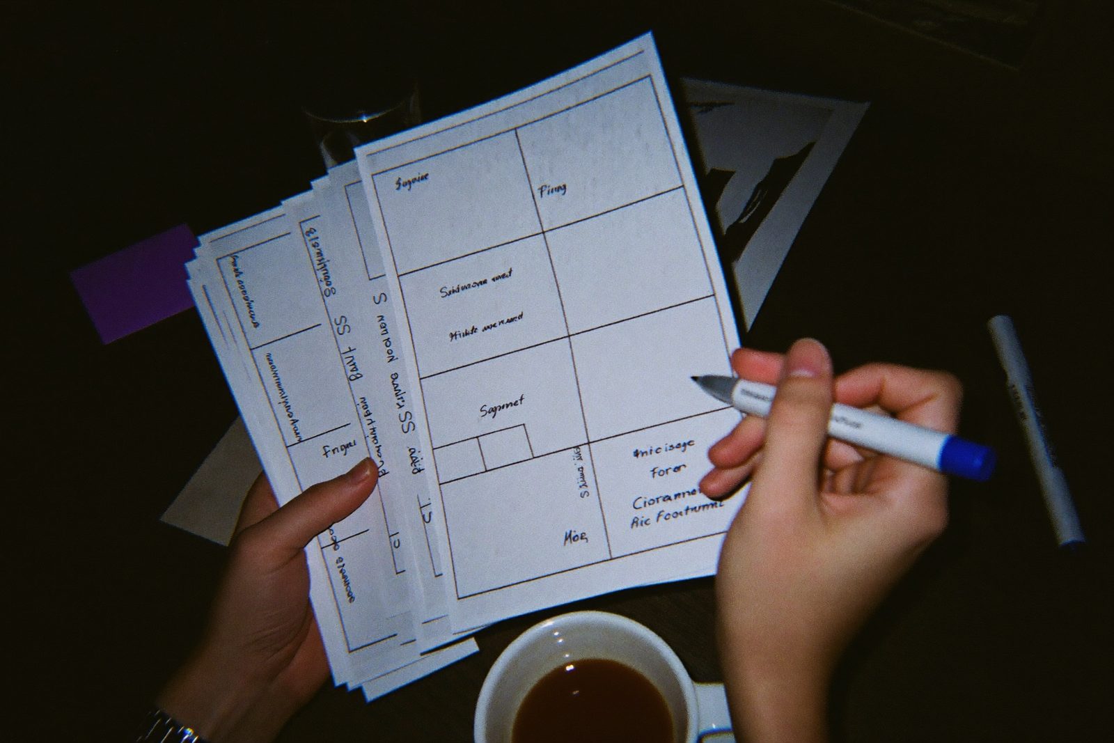 Hands holding printed storyboard frames over a dark table